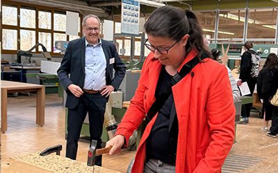 Eine Frau schlägt einen Nagel in ein Holzbrett